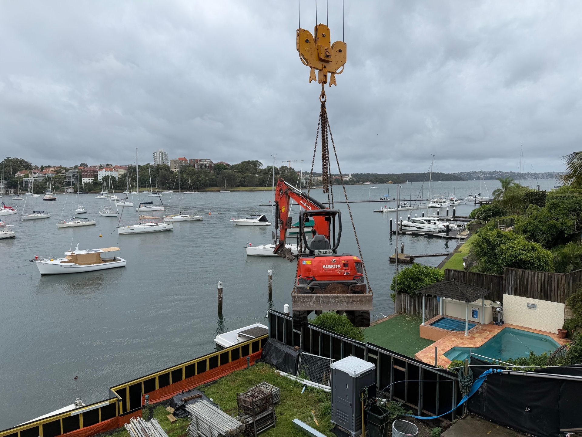 Excavator craned over Sydney Harbour at a waterfront demolition site